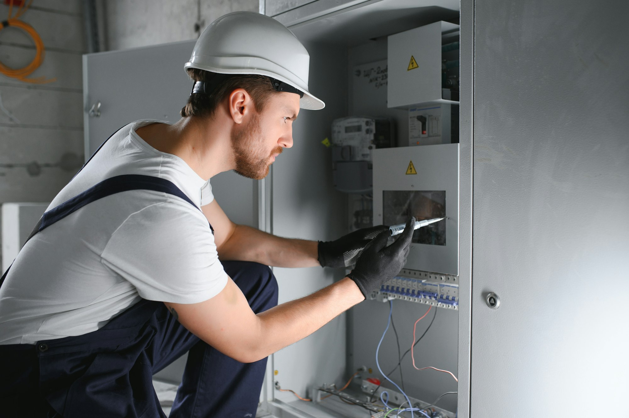 Man, an electrical technician working in a switchboard with fuses.